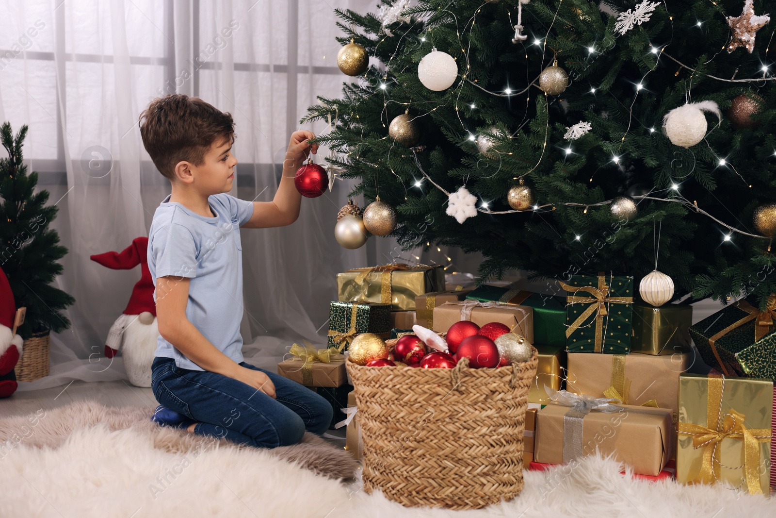 Photo of Cute little child decorating Christmas tree at home