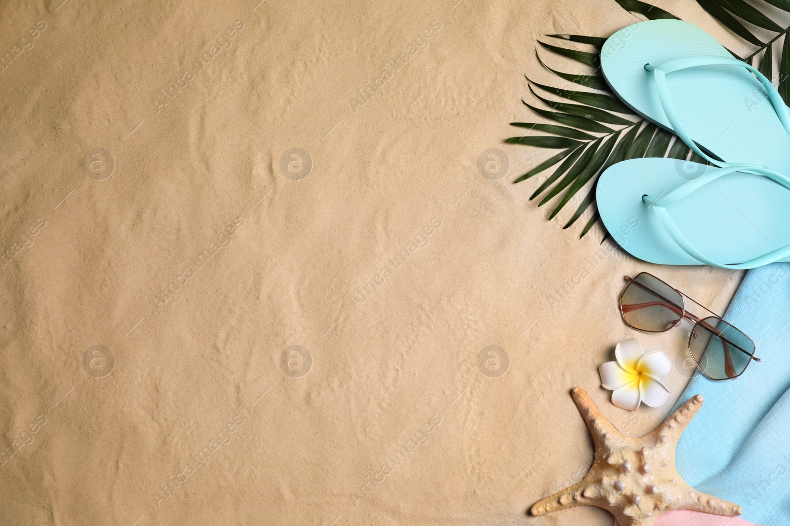 Photo of Beach accessories on sand, flat lay. Space for text