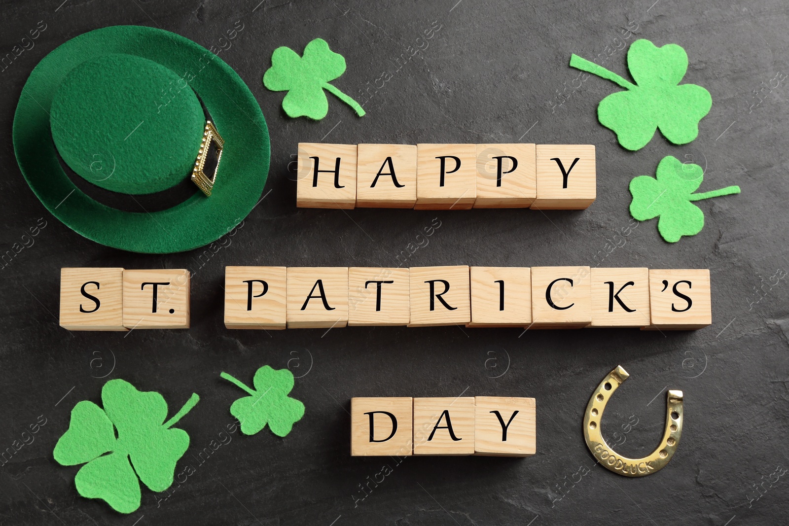 Photo of Words Happy St. Patrick's day, hat and festive decor on black slate background, flat lay