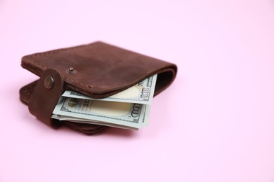 Photo of Stylish brown leather wallet with dollar banknotes on pink background, closeup. Space for text