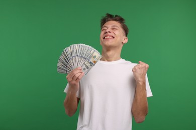 Photo of Happy man with dollar banknotes on green background