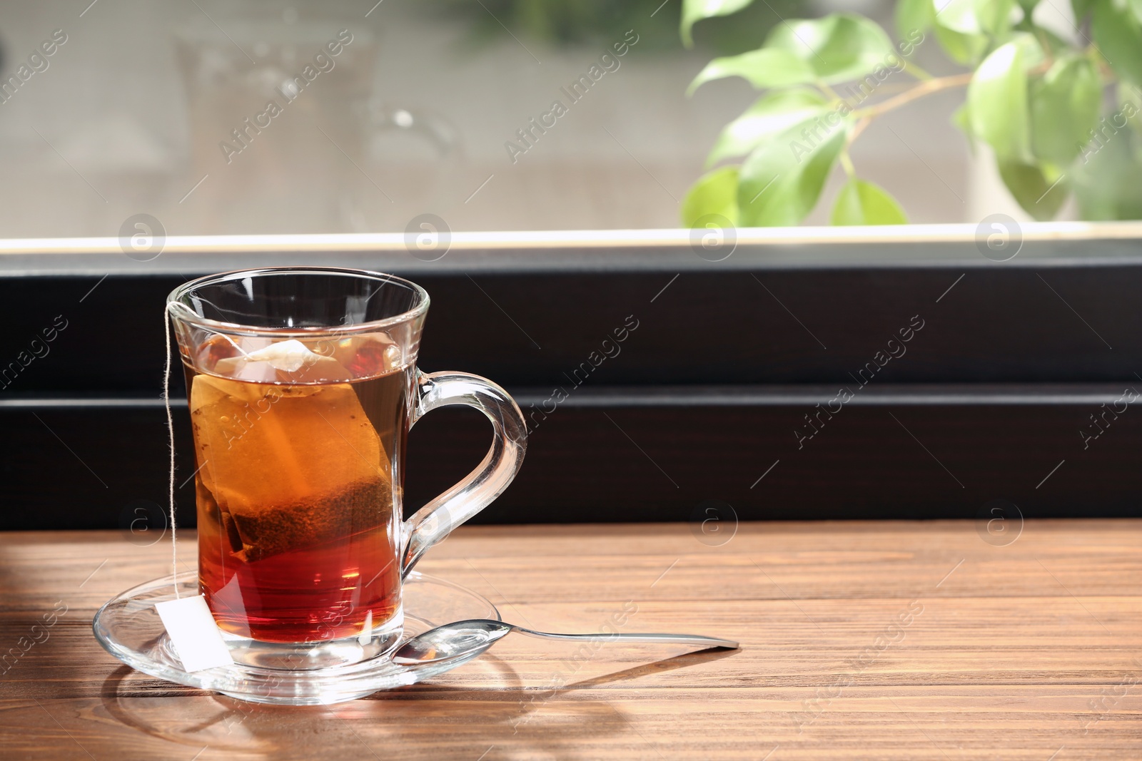 Photo of Glass cup of hot tea on wooden window sill. Space for text