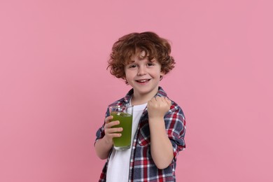 Cute little boy with glass of fresh juice on pink background