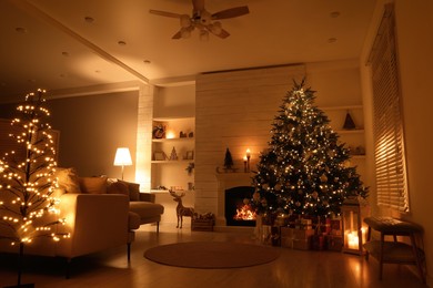 Beautiful Christmas tree and gift boxes near fireplace in festively decorated living room