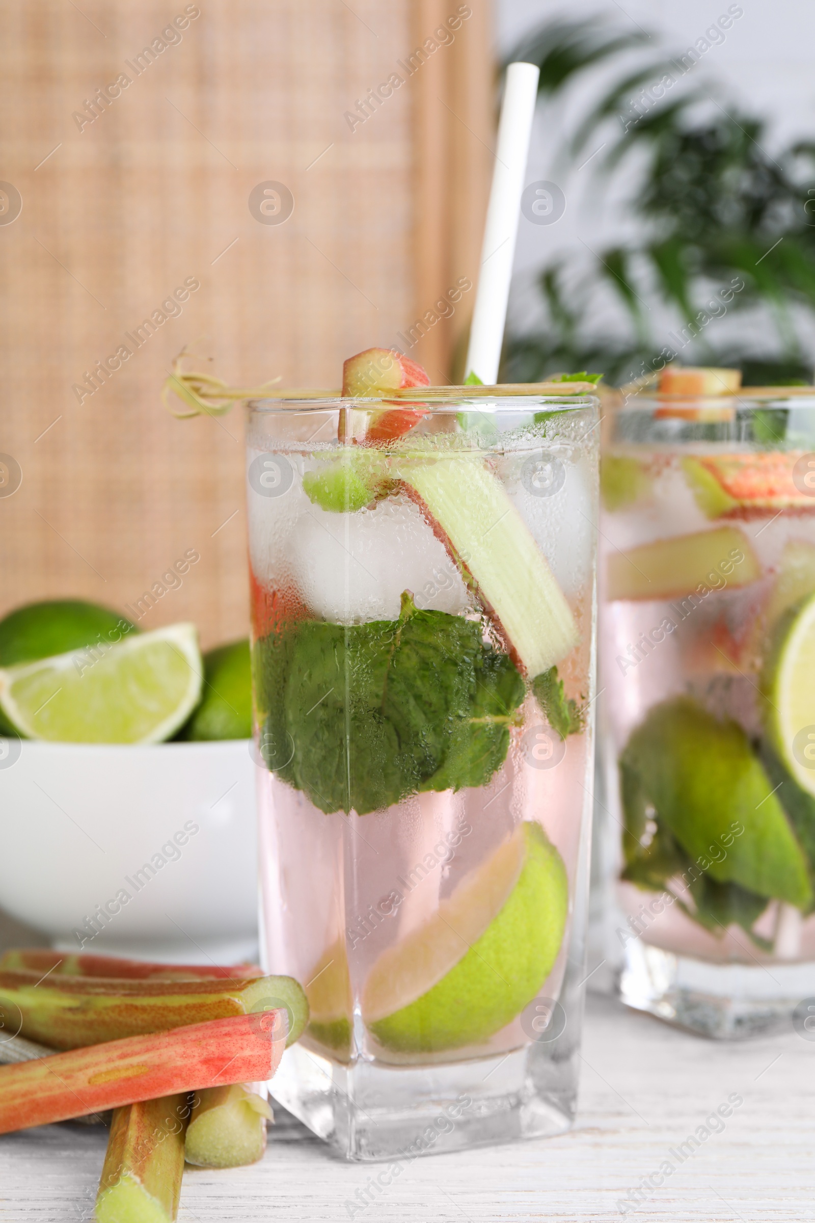 Photo of Tasty rhubarb cocktail with lime on white wooden table, closeup