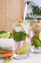 Tasty rhubarb cocktail with lime on white wooden table, closeup