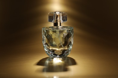 Photo of Luxury women's perfume. Sunlit glass bottle on golden background