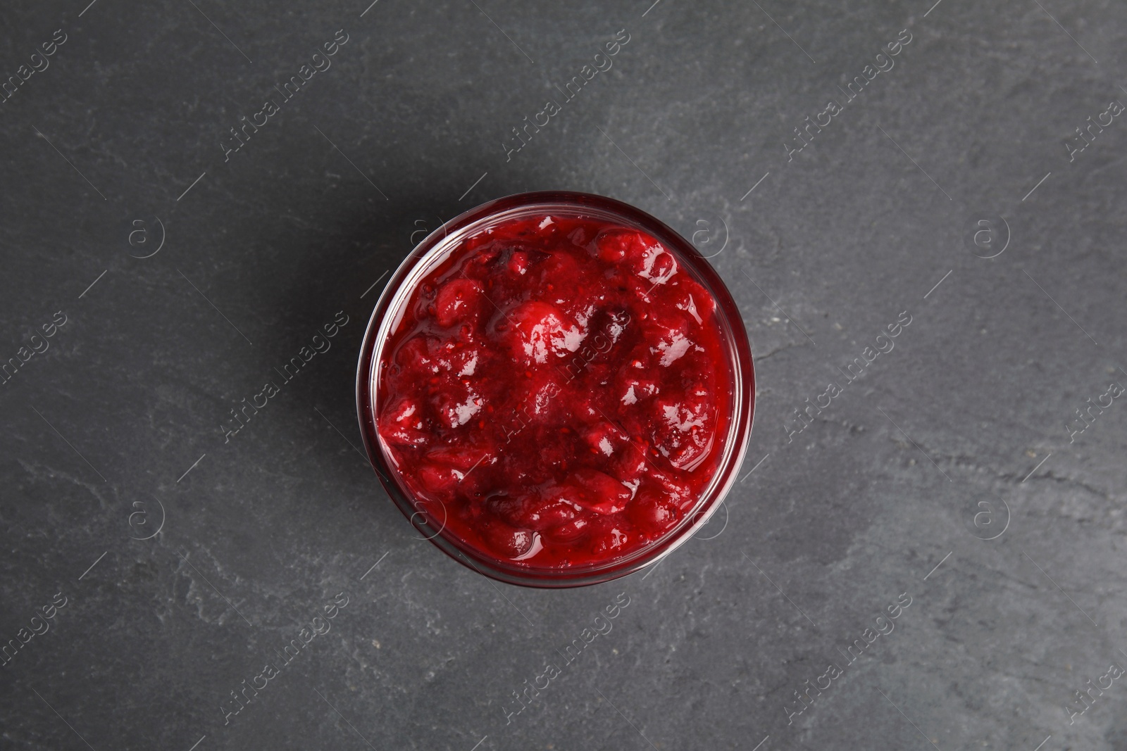 Photo of Bowl of cranberry sauce on grey background, top view