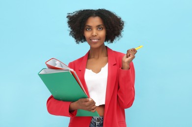 Photo of African American intern with folders and pen on light blue background