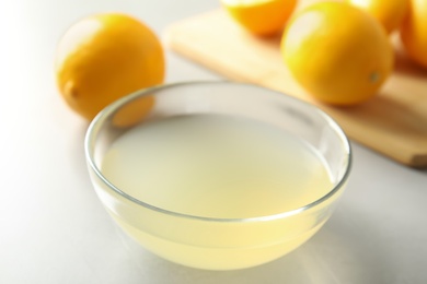 Freshly squeezed lemon juice in bowl on light table, closeup