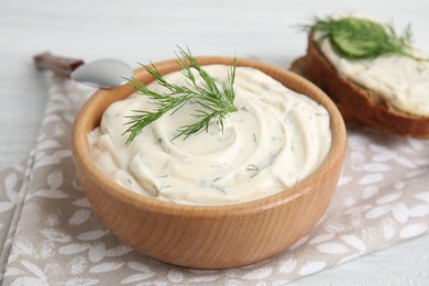 Photo of Tasty creamy dill sauce in wooden bowl on table, closeup