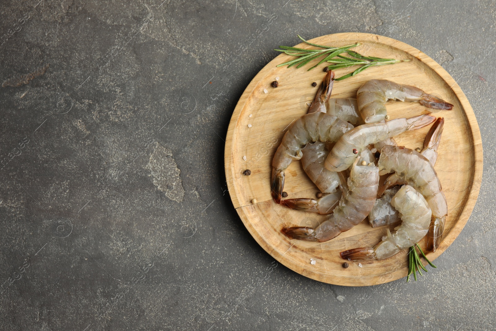 Photo of Fresh raw shrimps with rosemary on grey table, top view. Space for text