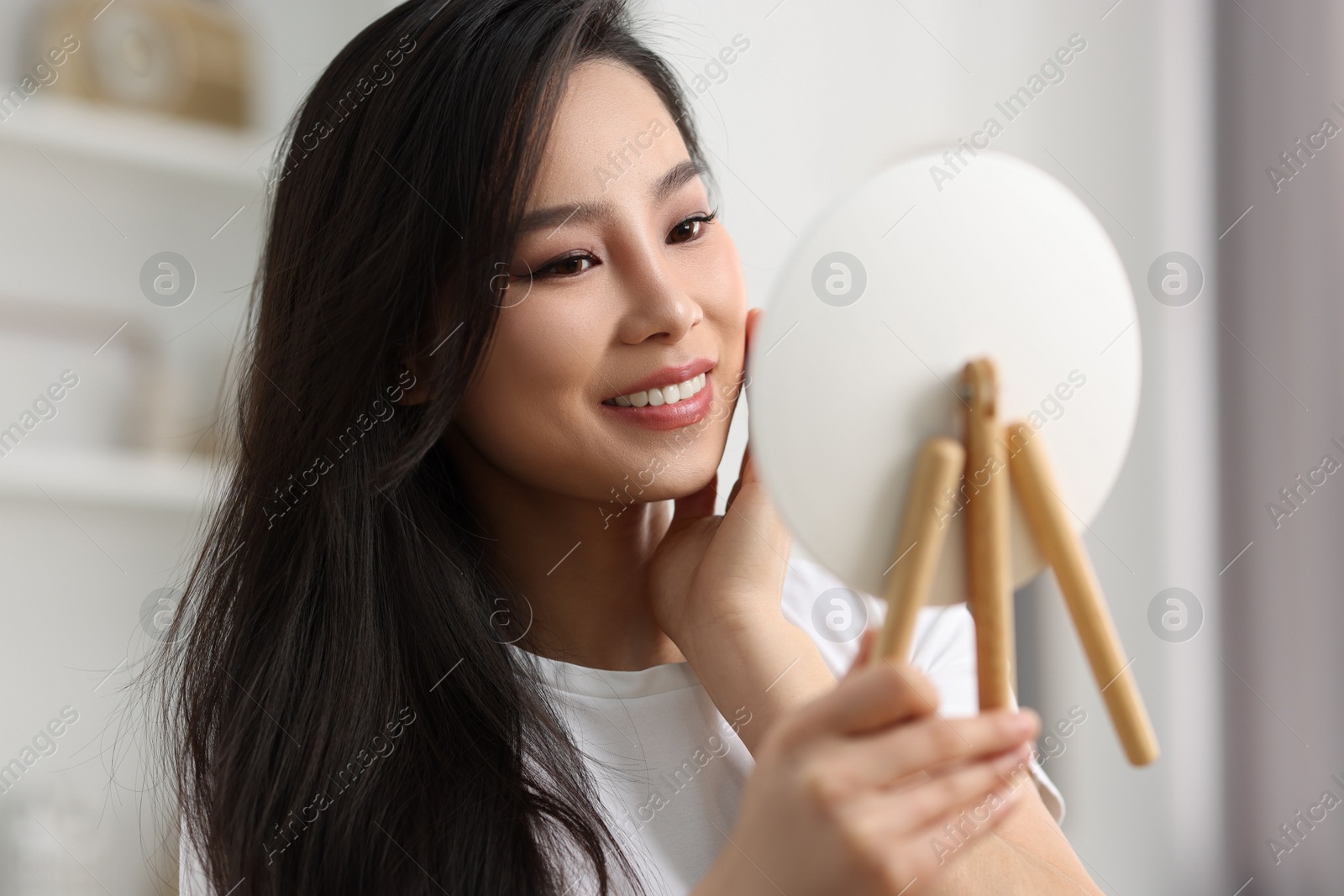 Photo of Woman with perfect skin looking at mirror indoors