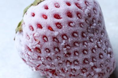 Photo of One frozen ripe strawberry on light table, closeup