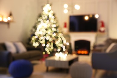 Blurred view of room with beautiful Christmas tree near fireplace