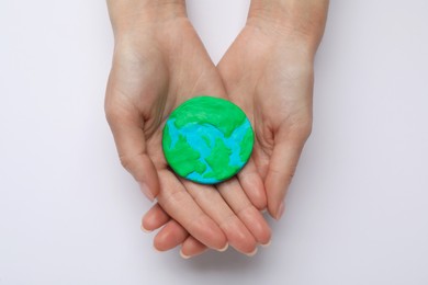 Photo of Woman holding plasticine model of planet on white background, top view. Earth Day