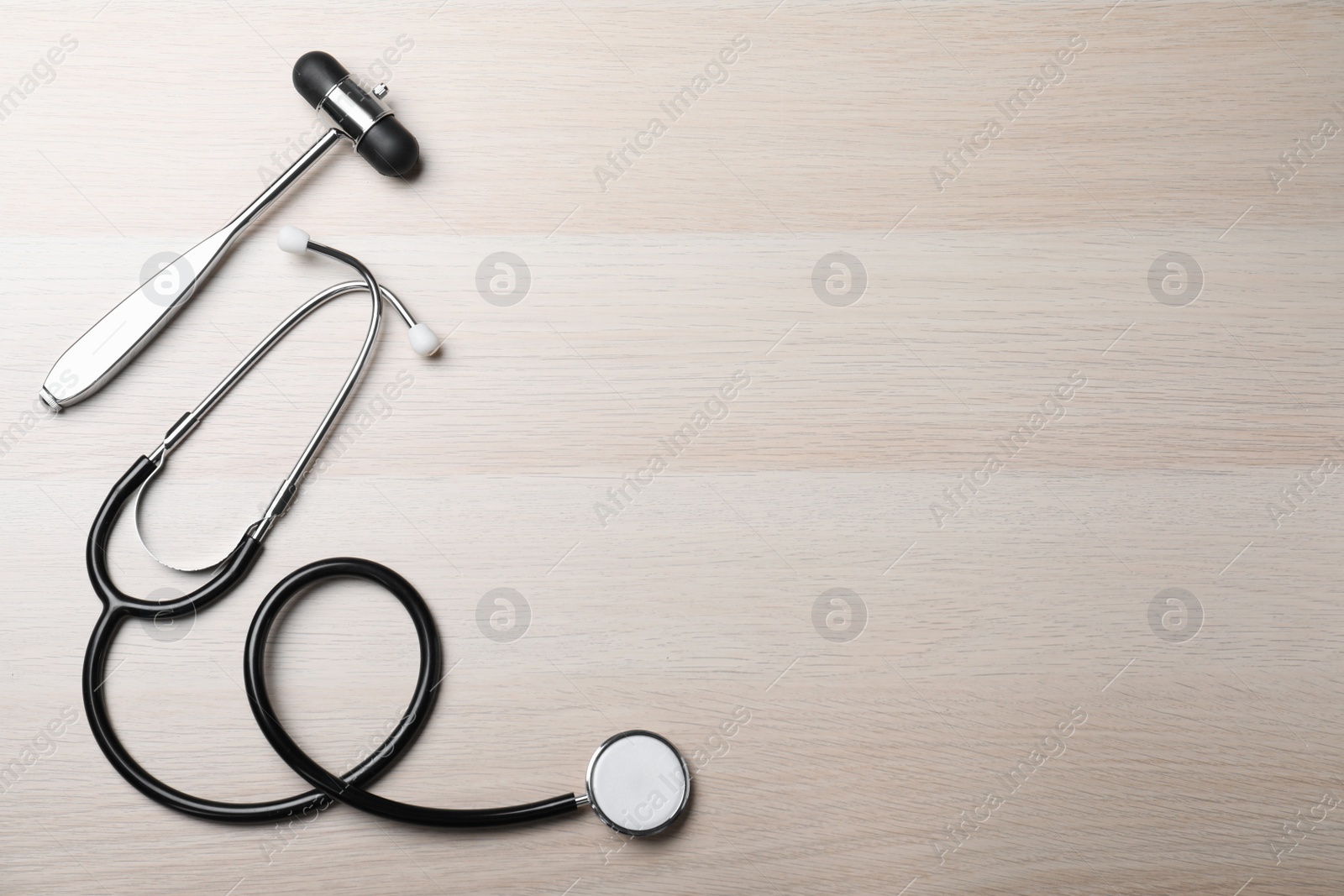 Photo of Reflex hammer with stethoscope on wooden background, flat lay and space for text. Nervous system diagnostic