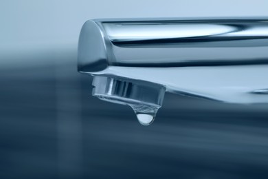 Image of Water drop falling down from tap on blurred background, closeup