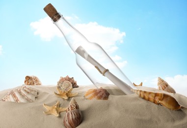 Corked glass bottle with rolled paper note and seashells on sand against sky