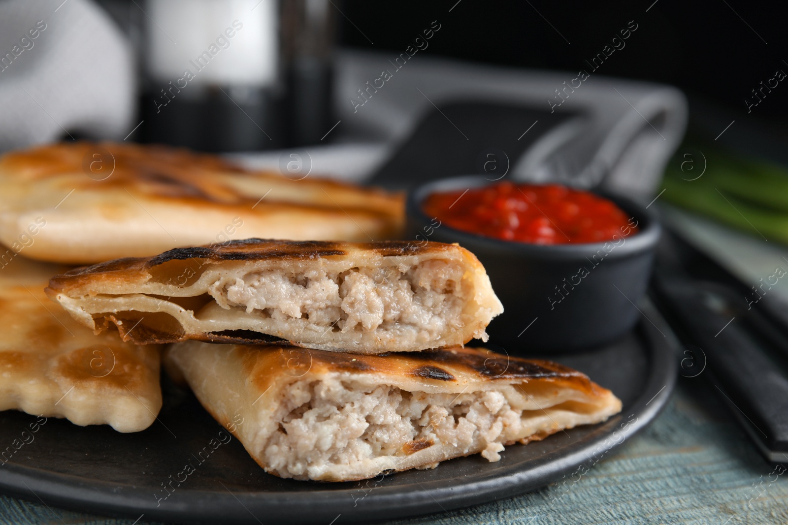 Photo of Delicious fried chebureki on blue wooden table, closeup