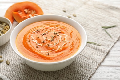 Photo of Bowl with tasty pumpkin soup served on table