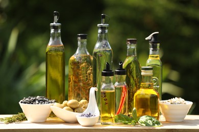 Photo of Different cooking oils and ingredients on wooden table against blurred green background