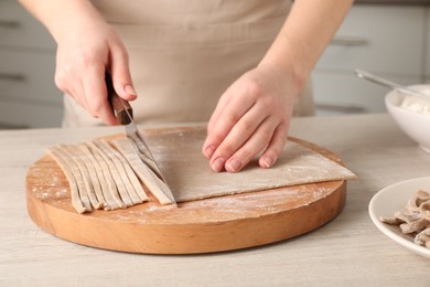 Photo of Woman making soba (buckwheat noodles) at wooden table, closeup