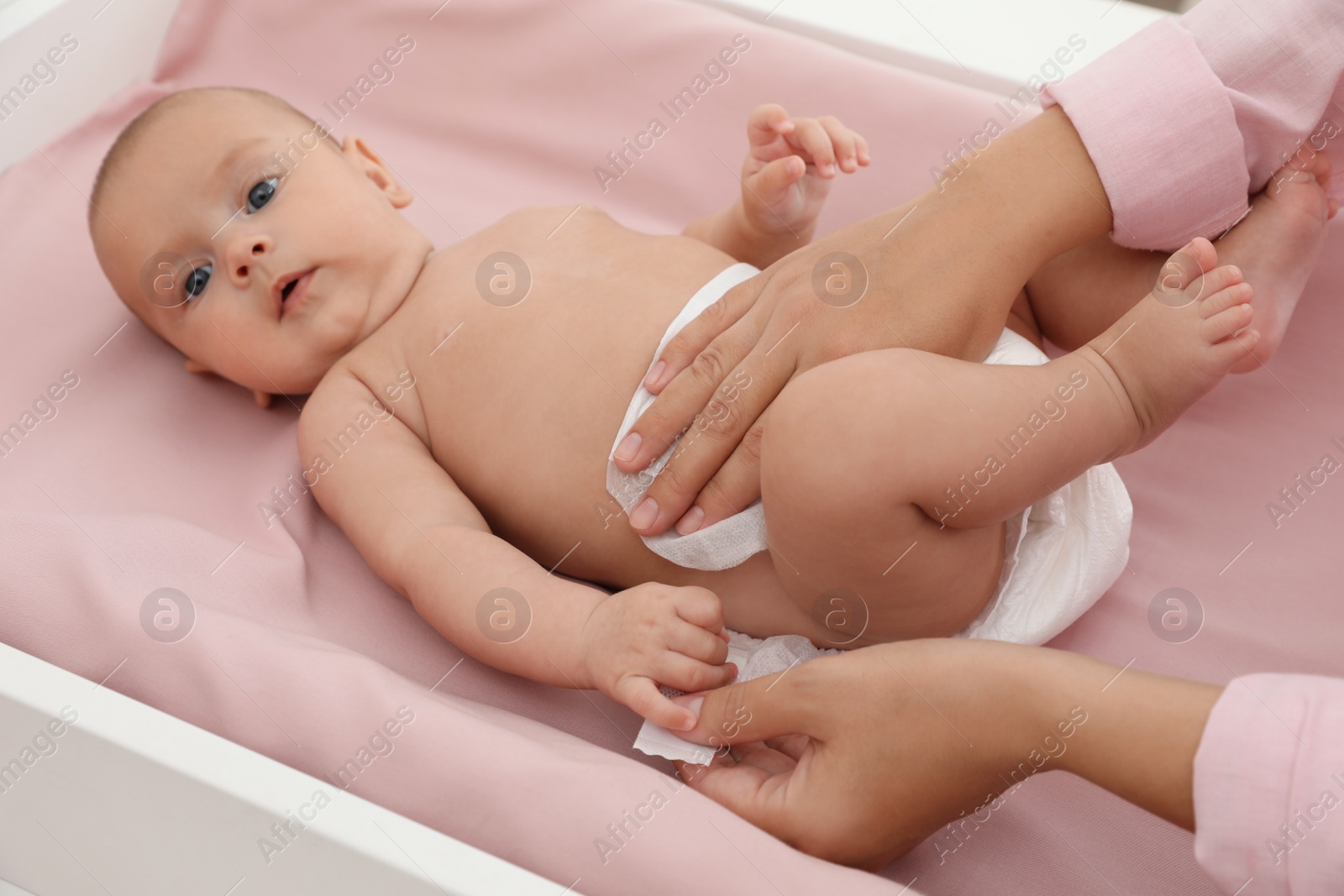 Photo of Mother changing her baby's diaper on table