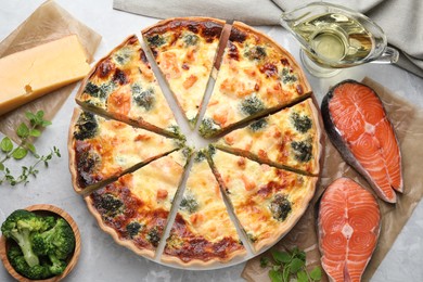Photo of Delicious homemade quiche and ingredients on light gray table, flat lay