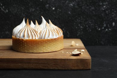 Tartlet with meringue on black table, closeup and space for text. Delicious dessert