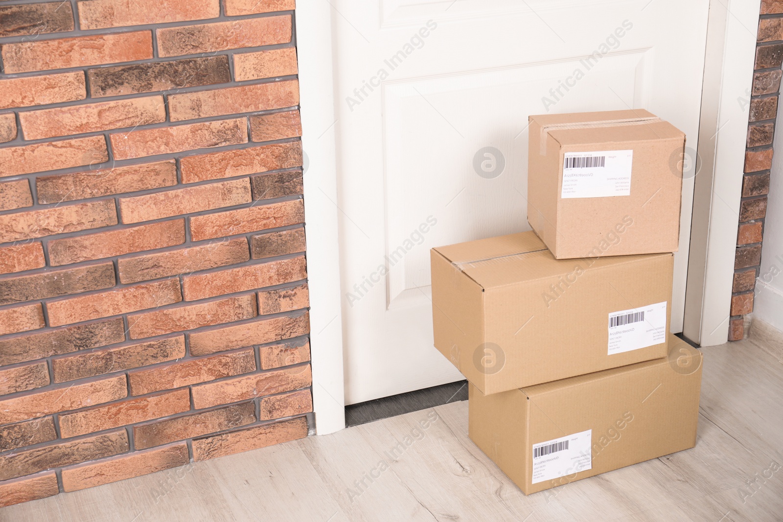 Photo of Cardboard parcel boxes on floor near apartment entrance. Mockup for design