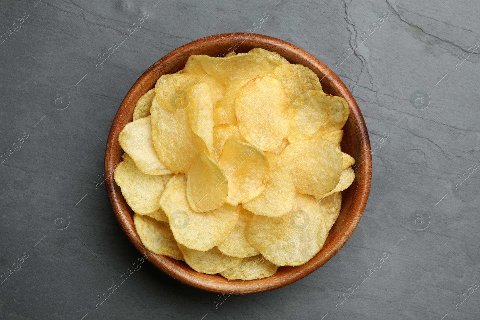 Photo of Bowl of potato chips on grey table, top view