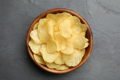 Bowl of potato chips on grey table, top view