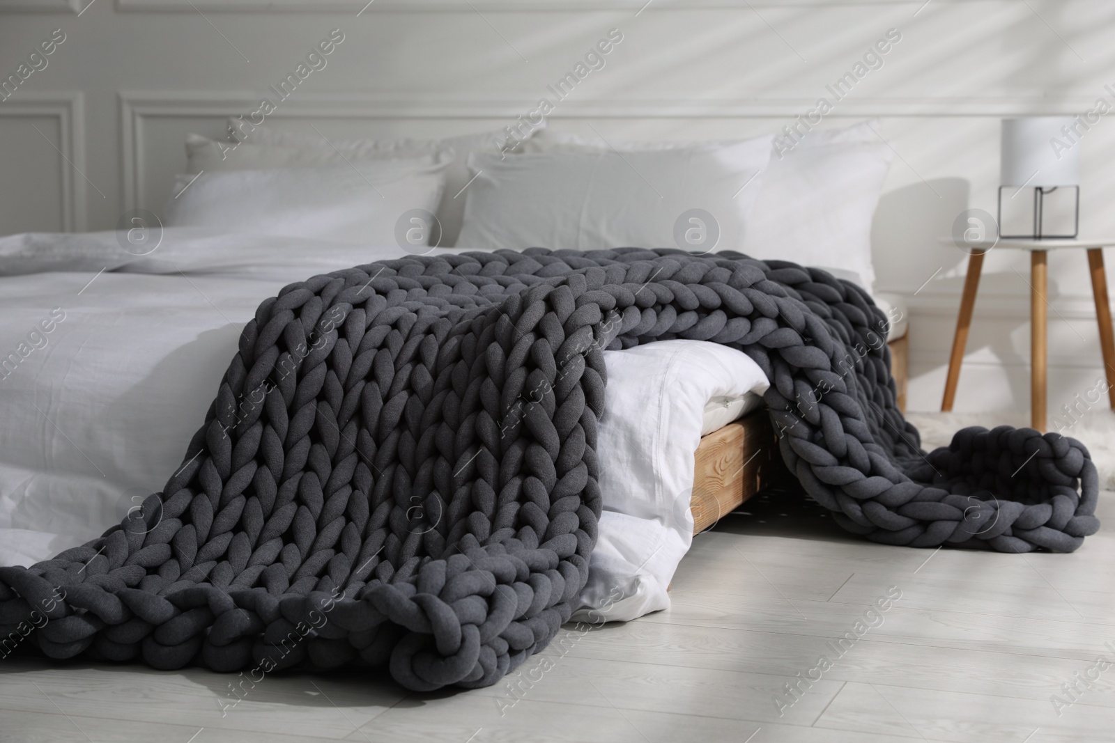 Photo of Soft chunky knit blanket on bed in stylish room interior