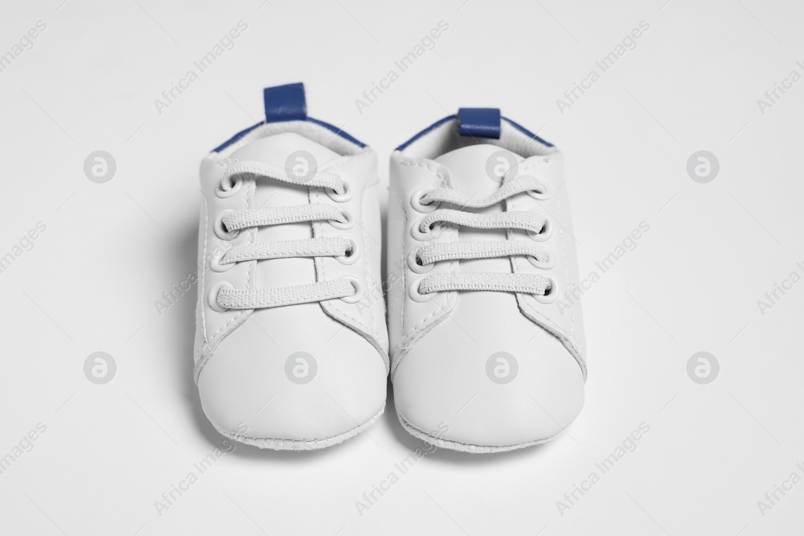 Photo of Pair of cute baby shoes on white background