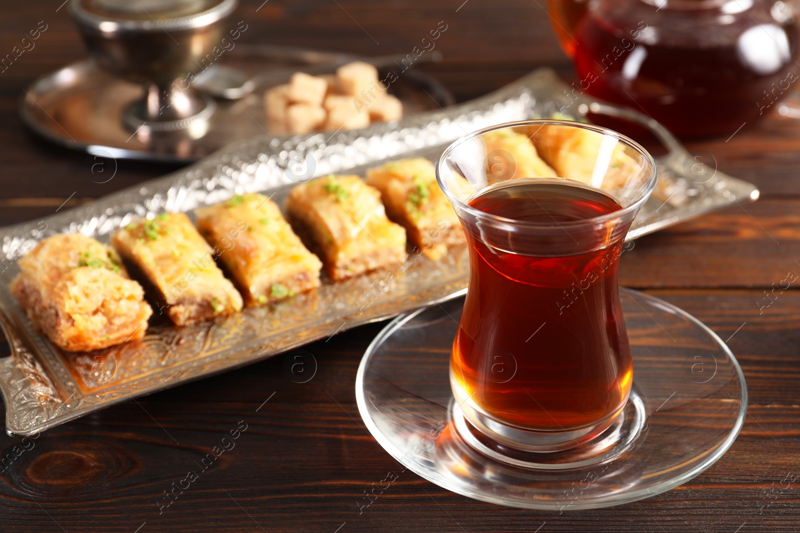 Photo of Traditional Turkish tea in glass and fresh baklava on wooden table