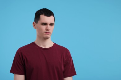 Portrait of sad man on light blue background, space for text