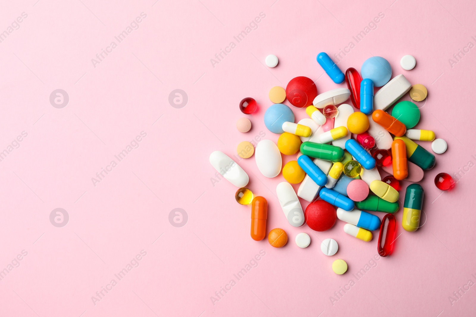 Photo of Pile of different pills on color background, top view. Space for text