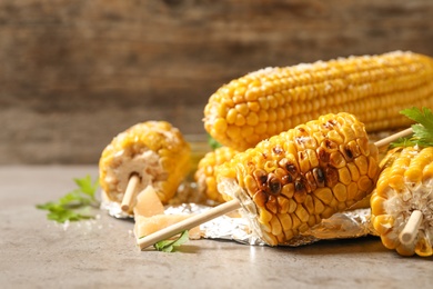 Delicious grilled corn cobs on grey table. Space for text