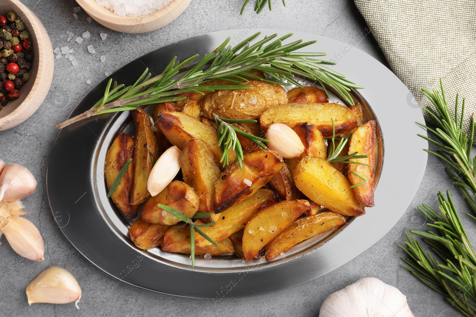 Photo of Tasty baked potato and aromatic rosemary on grey textured table, flat lay