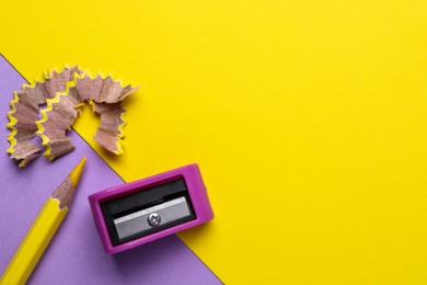 Photo of Yellow pencil, shavings and sharpener on color background, flat lay. Space for text