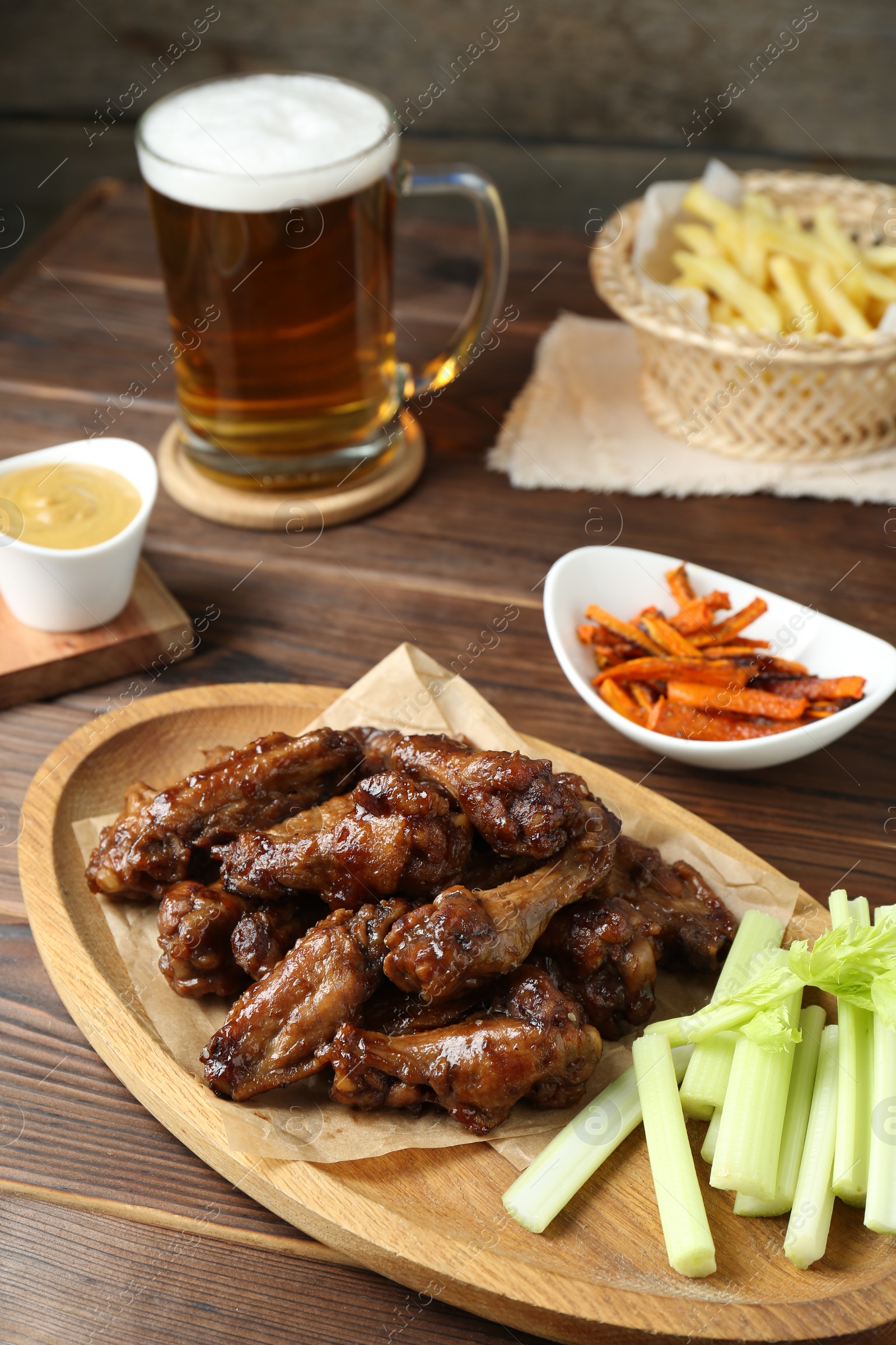 Photo of Delicious chicken wings served with beer on wooden table