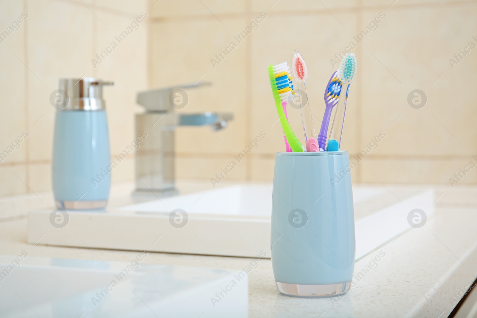 Photo of Cup with different toothbrushes near sink in bathroom. Dental care