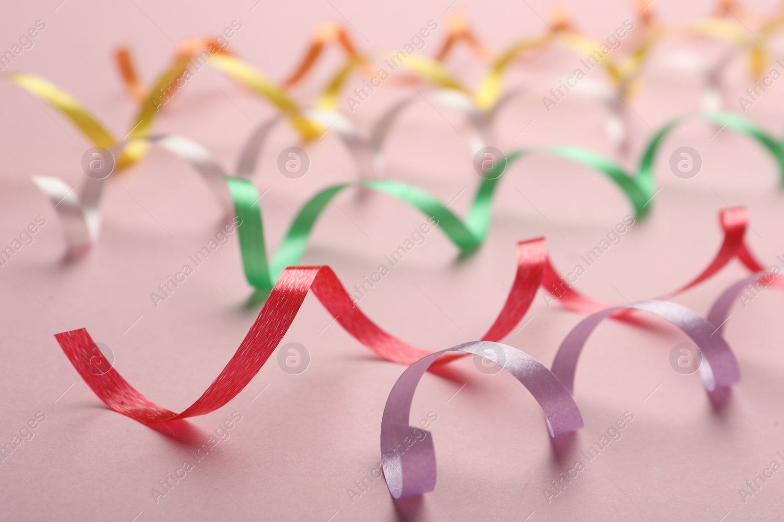 Photo of Colorful serpentine streamers on pink background, closeup