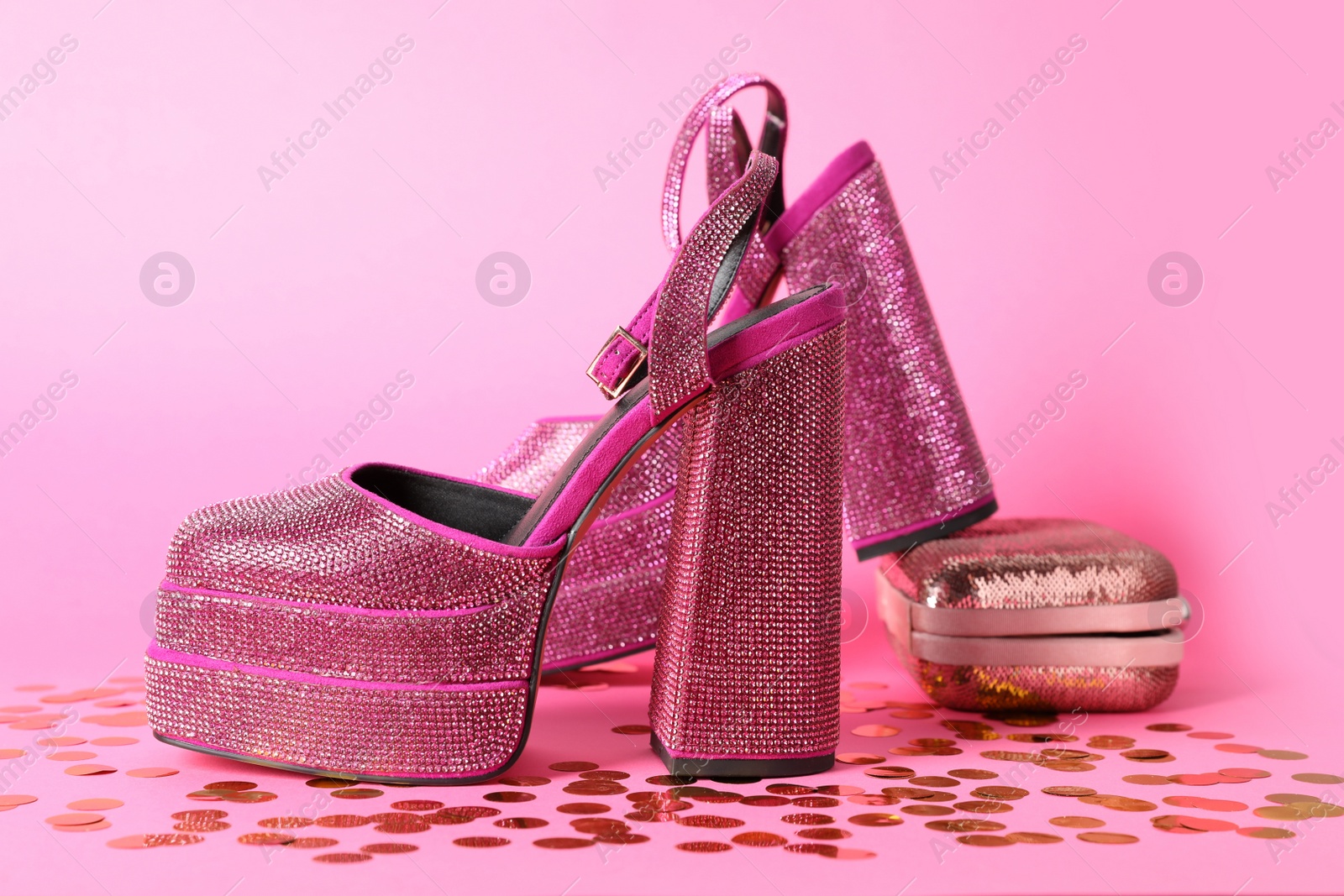 Photo of Fashionable punk square toe ankle strap pumps and confetti on pink background. Shiny party platform high heeled shoes