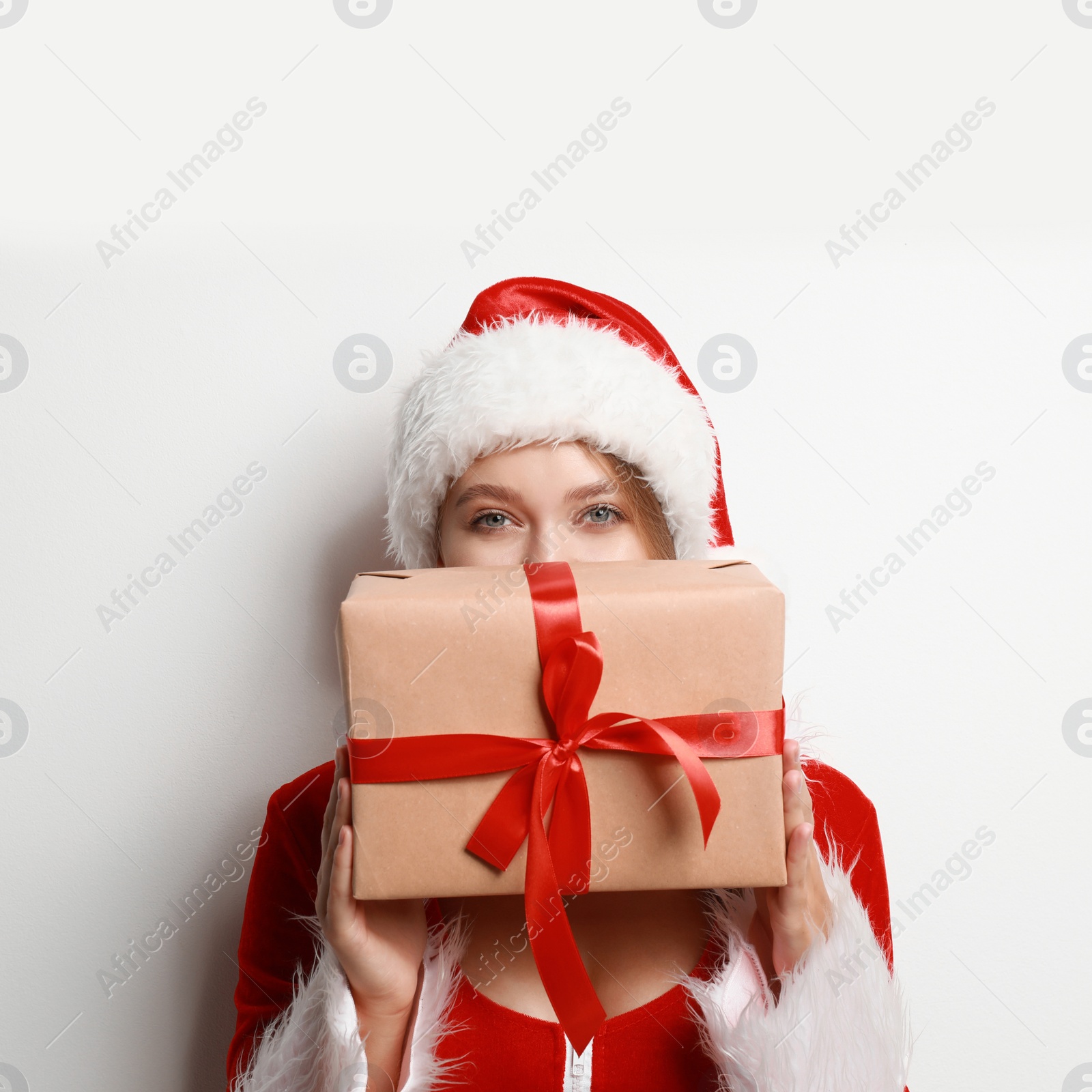 Photo of Beautiful Santa girl with Christmas gift on light background