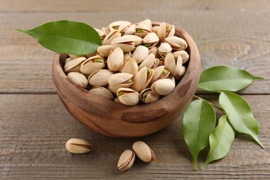 Delicious pistachios in bowl on wooden table