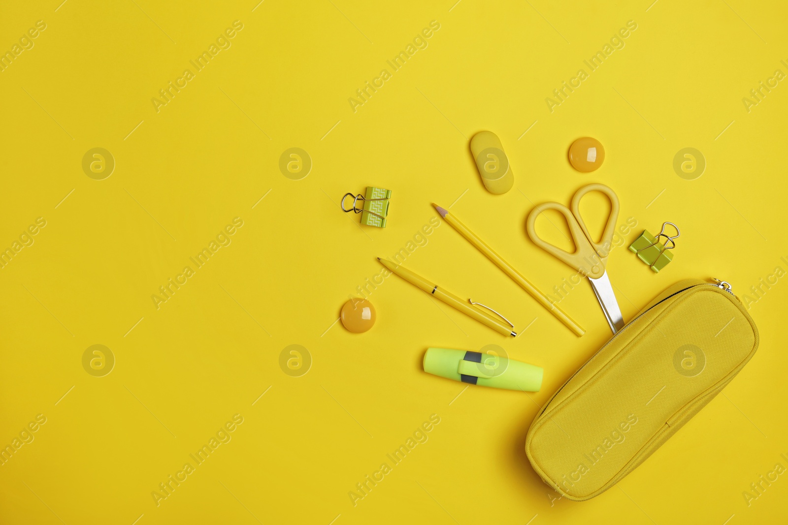 Photo of Flat lay composition with pencil box and stationery on yellow background. Space for text
