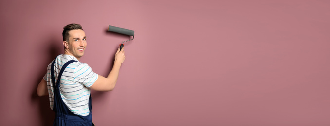 Professional decorator with paint roller near pink wall, space for text. Banner design