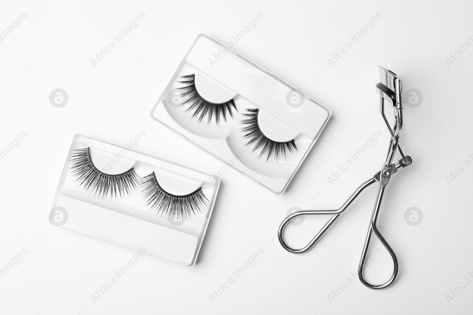 Photo of Flat lay composition of curler and false eyelashes on white background